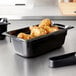 A close-up of a Vollrath black plastic food pan with fried chicken inside.
