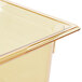 A Vollrath 1/2 size high heat amber plastic food pan on a counter in a school kitchen.