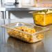Two Vollrath amber plastic food pans on a counter.