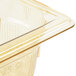 A Vollrath 1/9 size amber high heat plastic food pan with a lid on a counter in a salad bar.