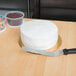 An Ateco offset baking icing spatula with a plastic handle on a table with a round white cake.