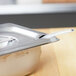 A stainless steel slotted cover for a Vollrath Super Pan 3 on a silver pan.