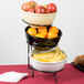 A Cal-Mil black iron three tier bowl stand with fruit in bowls on a hotel buffet table.