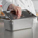 A hand opening a Vollrath stainless steel solid cover on a metal container.
