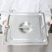 A person holding a Vollrath stainless steel slotted tray cover.