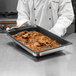 A chef holding a Vollrath Super Pan 3 with food in it.