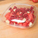 A clear plastic Sabert bowl with a clear plastic dome lid filled with fruit.