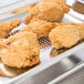 Fried chicken on a Vollrath stainless steel steam table pan.