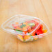 A clear Sabert plastic container with vegetables inside.