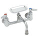 A chrome T&S wall mount faucet with two handles and two faucets.