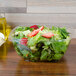A salad in a clear plastic Sabert catering bowl.