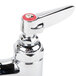 A close-up of a T&S chrome deck-mount faucet with red handles.