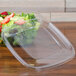 A Sabert clear plastic container lid on a plastic container filled with salad.