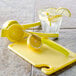 A Saf-T-Grip cutting board with a lemon, lemon slices, a lemon juicer, and a lemon squeezer.