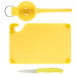A yellow Saf-T-Grip plastic cutting board with a knife and spoon.