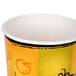 A Huhtamaki paper soup cup with a yellow and orange design.