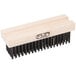 A close-up of a wooden FMP grill brush head with black bristles.