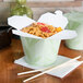 A SmartServ nature print take-out container of noodles with chopsticks on a table.