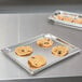 A stainless steel Vollrath 90202 Super Pan 3 with cookies on a counter.