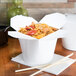 A white SmartServ microwavable paper take-out container with noodles.