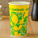 A yellow paper lemonade cup with a green design on a counter.