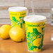 Two yellow paper lemonade cups with white lids next to lemons.