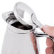 A hand holding a Bon Chef stainless steel server with the lid open.