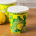 Two yellow Squat Paper Lemonade Cups with a white lid and straw on a counter.