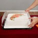 A person holding a D&W Fine Pack 1 1/2 size sheet cake in a plastic container with a clear lid.