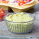 A clear fluted Carlisle ramekin filled with guacamole on a table.
