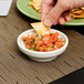 A person dipping a chip into a Carlisle bone salsa bowl filled with salsa.