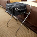 A black suitcase on a metal folding luggage rack.