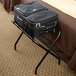 A black suitcase on a black CSL Metal Folding Luggage Rack.