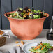 A Tablecraft copper cast aluminum tulip salad bowl filled with salad on a table.