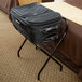 A black suitcase on a black CSL luxury folding luggage rack.
