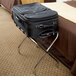 A black suitcase on a CSL metal folding luggage rack.
