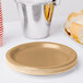 A stack of Creative Converting glittering gold paper plates with a gold rim.