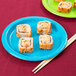 A turquoise blue Creative Converting paper plate with sushi and chopsticks on it.