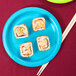 A turquoise blue Creative Converting paper plate with sushi on it.