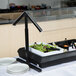 A Carlisle black adjustable double sneeze guard over a table with salads and plates.