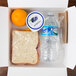 A white Fold-Pak Bio-Pak take-out box filled with a sandwich, orange, and a bottle of juice.