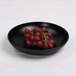 A black Elite Global Solutions melamine bowl with grapes on it.