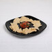 A black Elite Global Solutions square melamine plate with tortilla chips and salsa on it.
