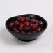A black Elite Global Solutions melamine bowl filled with cherries.