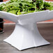 A white Carlisle melamine pedestal bowl filled with salad on a table.