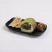An Elite Global Solutions black melamine two-compartment tray with food on it.