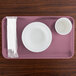 A purple Cambro rectangular tray with a white bowl and cup on it.