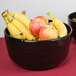 A Tablecraft black cast aluminum fruit bowl with green speckles filled with bananas and apples on a table.