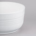 A Tablecraft white cast aluminum fruit bowl with a handle on a white surface.