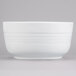 A white Tablecraft cast aluminum fruit bowl with a white rim on a gray background.